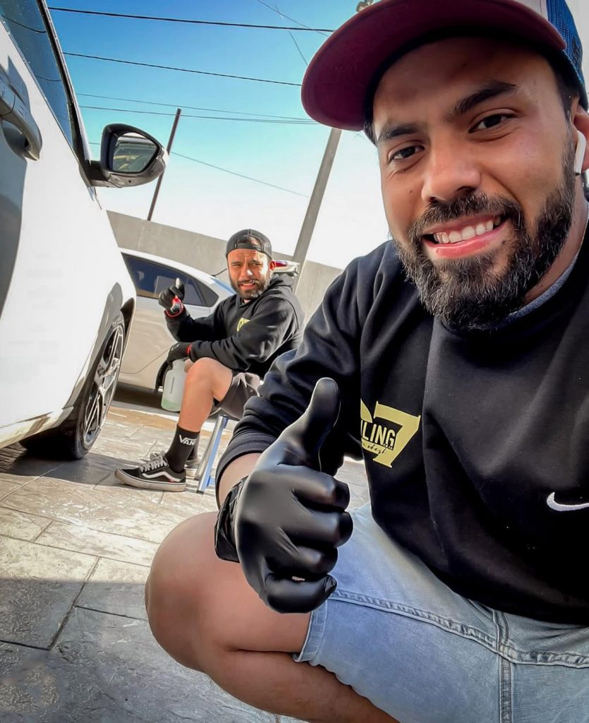 hombres jóvenes realizando detallado o lavado de coche detailing y pulido